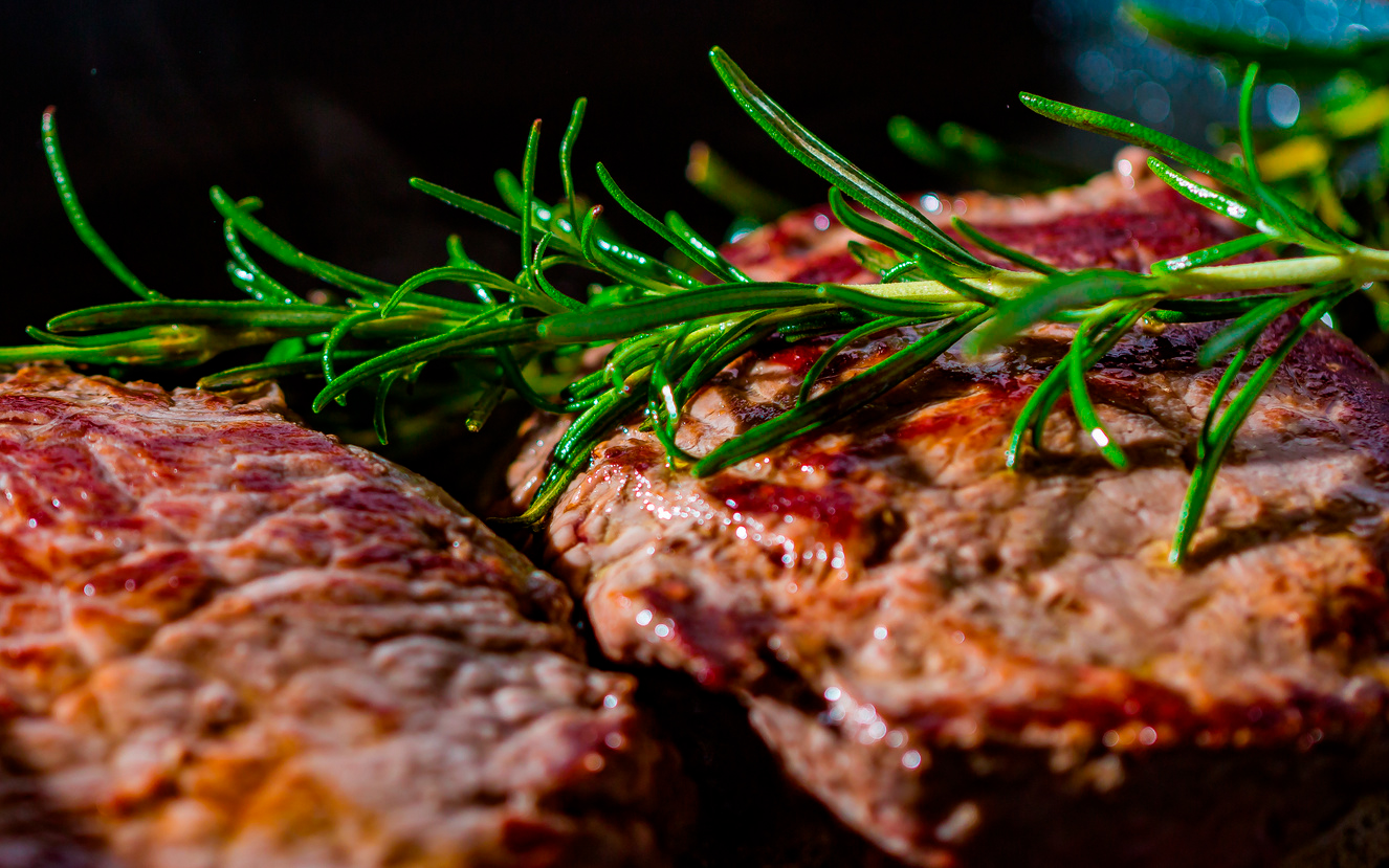 Carnes de churrasco com alecrim e paisagem de fazenda ao fundo